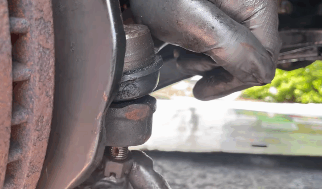 Photo showing mechanic disconnecting tie rods from a car
