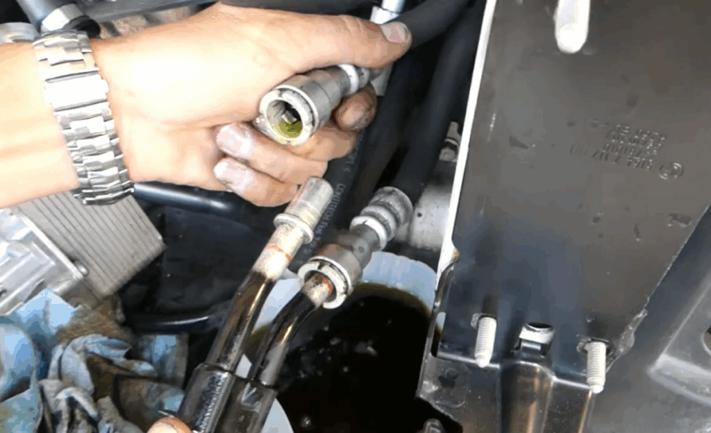 Photo showing mechanic disconnecting power steering fluid lines 