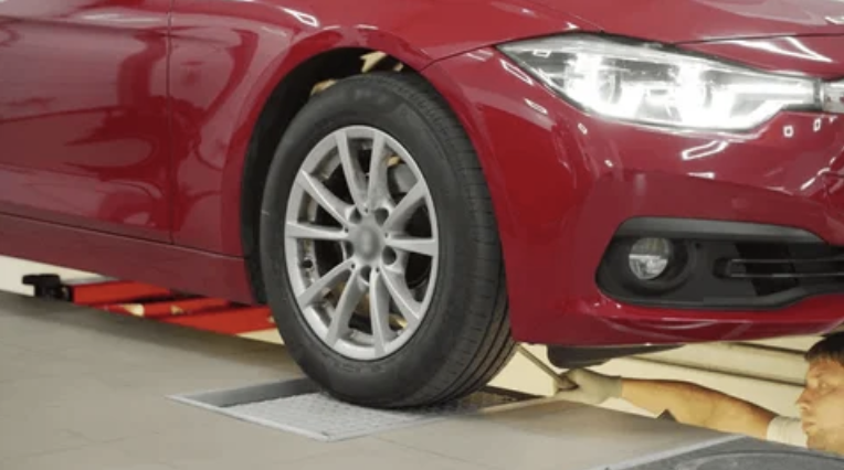 red car's tire being inspected